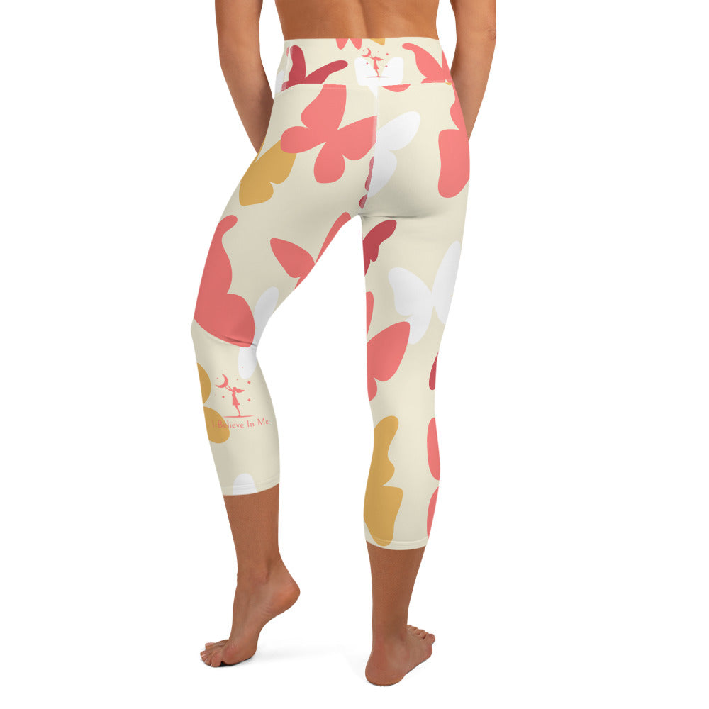 rear view of a barefoot woman wearing cream colored capri length yoga pant with large pink and yellow butterflies 