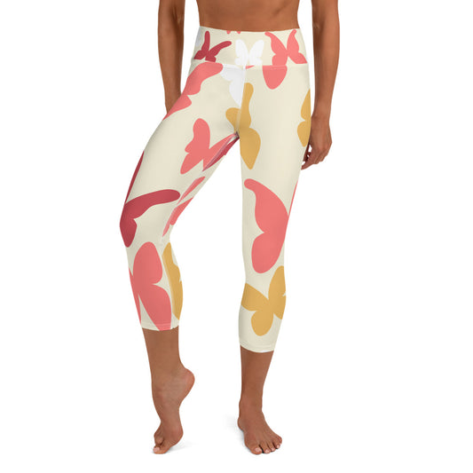 front view of a barefoot woman wearing cream colored capri length yoga pant with large pink and yellow butterflies 